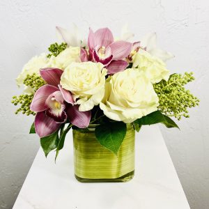 Pink Orchids for the Desk. Leaf lined cube vase with white roses, pink and white cymbidium orchids designed by La Paloma Blanca Floral Designed in Scottsdale, AZ