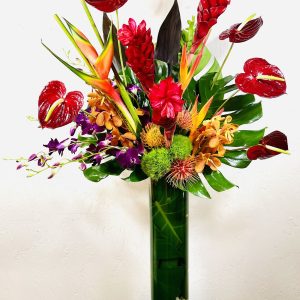 24" Cylinder with red ginger, red anthurium, orange heliconia, purple dendrobium orchids, orange mokara ochids, orange pincushion protea, monstera leaves, and green trick designed by La Paloma Blanca Floral Designs in Scottsdale, AZ