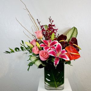 Pink stargazer lilies, red anthurium, james story orchids, and pink roses