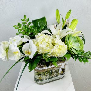 Medium oval vase with white phalaenopsis orchids, white hydrangea, white oriental lilies, and a succulent designed by La Paloma Blanca Floral Designs in Scottsdale AZ