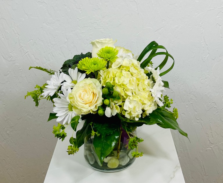 clear cylinder with white roses, white hydrangea, green kale, white daisies, and green button poms designed by La Paloma Blanca Floral Designs