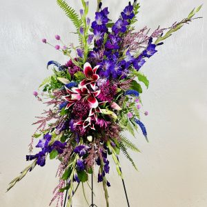 standing spray of dark purple gladiolus, stargazer lilies, purple cremones, gomphrenia, blue veronica,