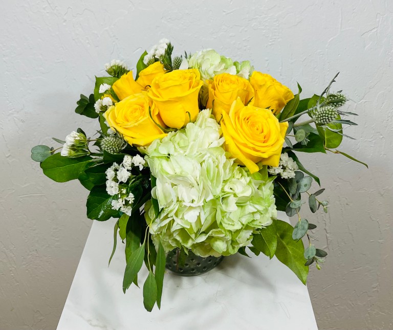 Yellow roses, green hydrangea, thistle and statice in a small hobnail jar designed by La Paloma Blanca Floral Designs