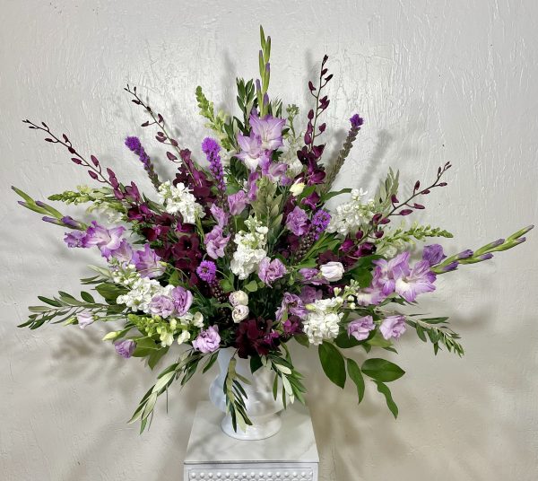 Purple Majesty white urn filled dark purple dendrobium orchids, purple gladiolus, white stock, purple liatris, and white snapdragons designed by la paloma blanca floral designs in scottsdale, az