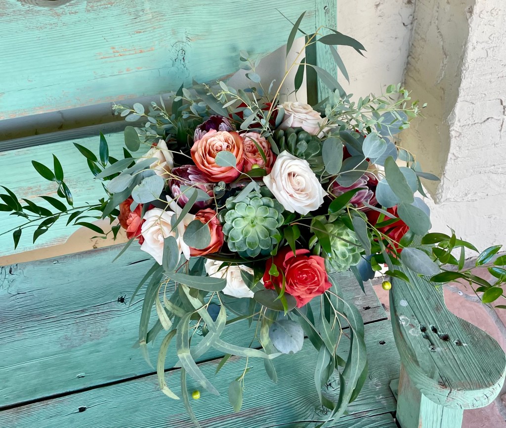 bridal bouquet of succulent, orange roses, white roses, and lots of eucalyptus greens